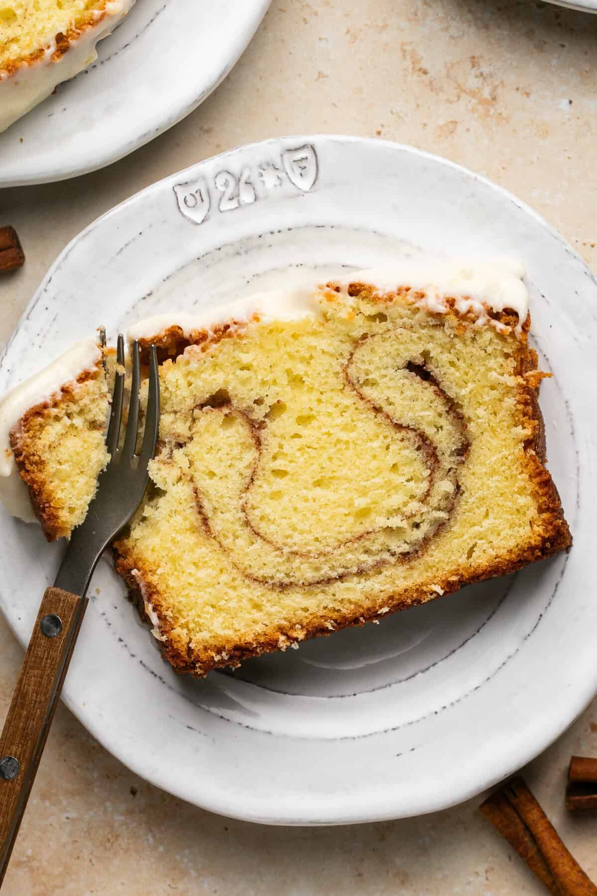 Overhead of a slice of cinnamon roll pound cake on a white plate with a fork.