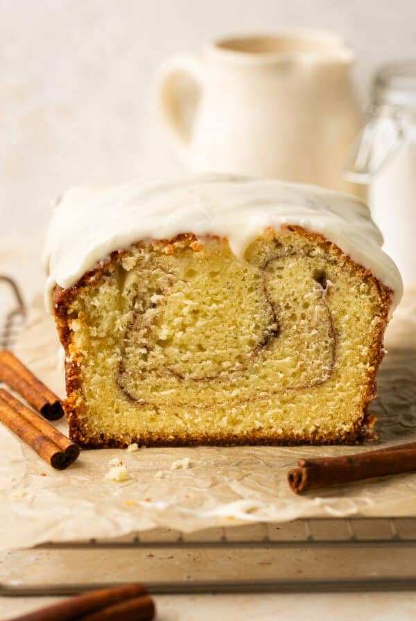 A cinnamon roll pound cake loaf with a slice missing.