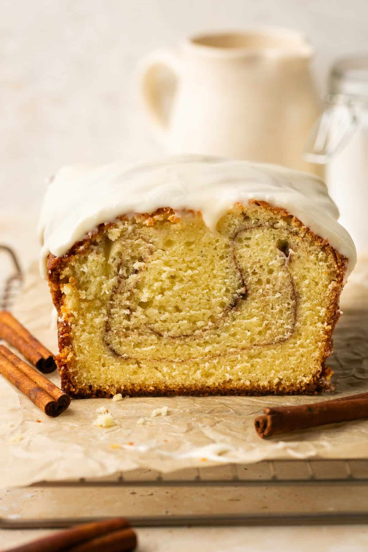 A cinnamon roll pound cake loaf with a slice missing.