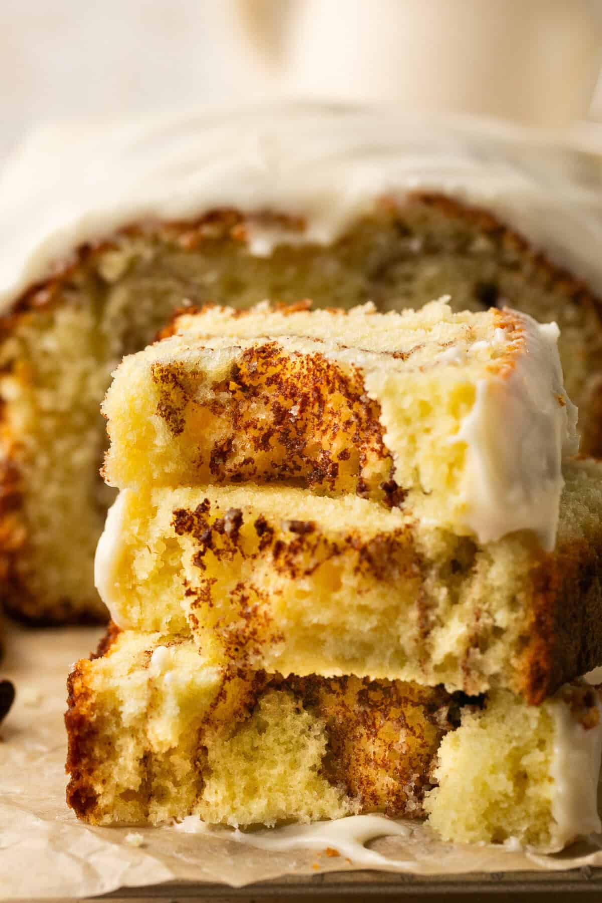 A stack of slices of cinnamon roll pound cake in front of the rest of the loaf.