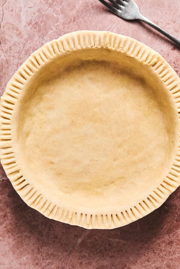 Unbaked gluten free pie crust on table with fork.