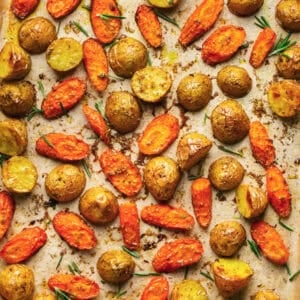 Overhead close up of roasted potatoes and carrots on a baking sheet.