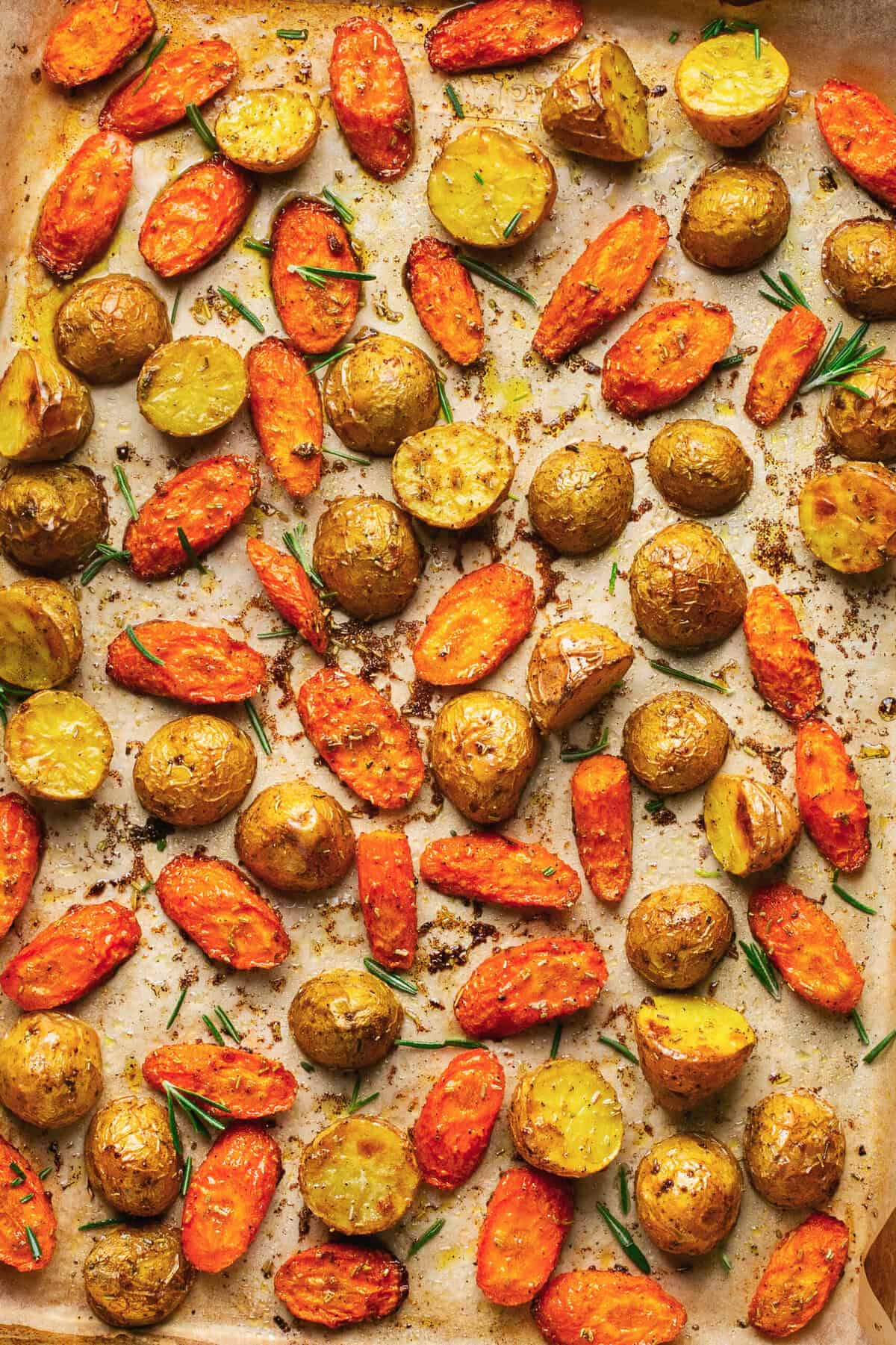 Overhead close up of roasted potatoes and carrots on a baking sheet.