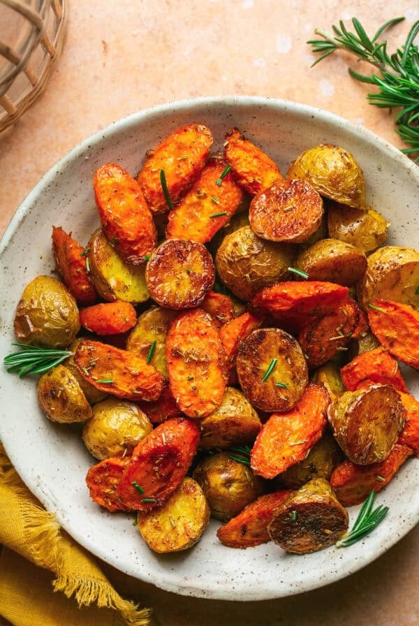 Overhead of roasted potatoes and carrots in a white dish.