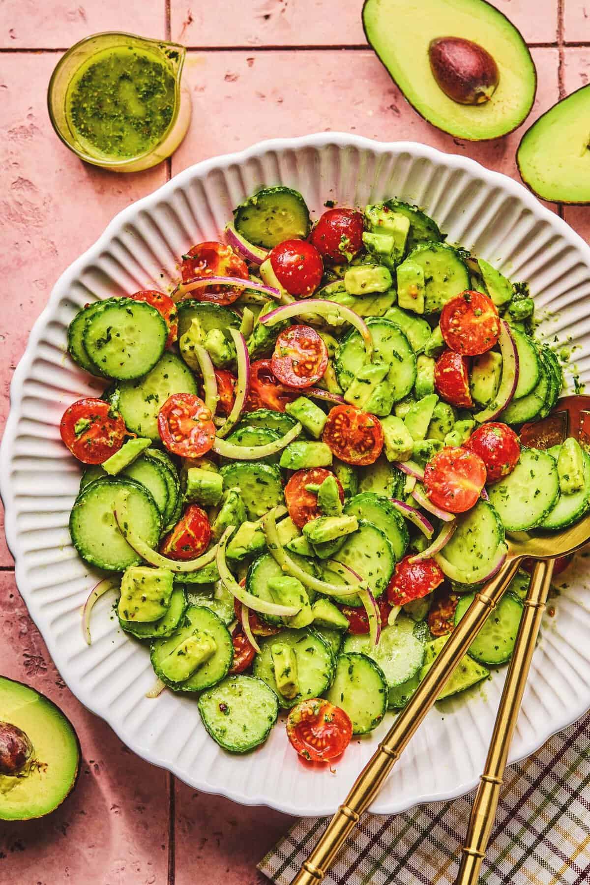 Overhead of avocado salad with serving utensils in a serving bowl.