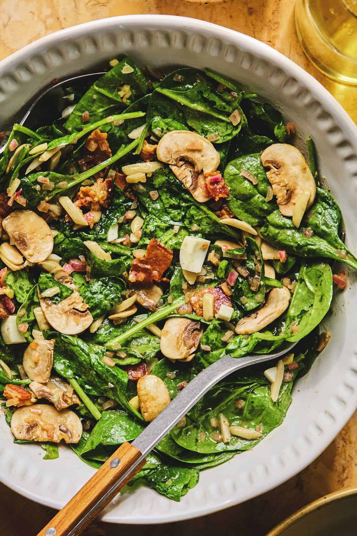 Overhead of spinach salad with hot bacon dressing.